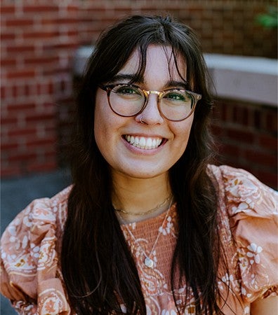 Photo of a student wearing glasses and a pink floral blouse.