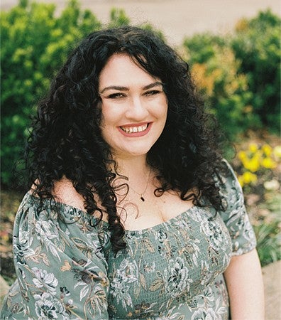 A student sitting outside in a floral blouse.