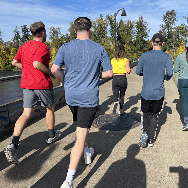 A group of people running on a bridge over a river.