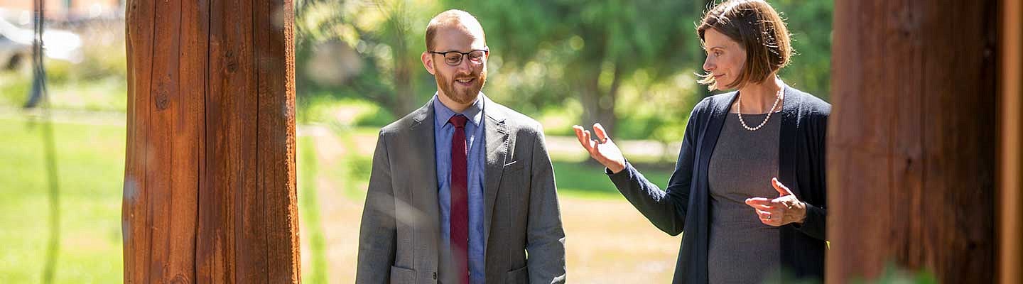 A student and professor have a discussion while walking outside