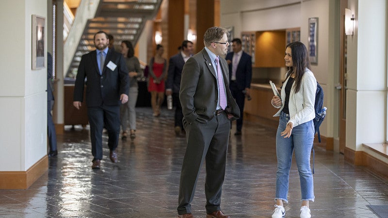 professor and student walking down a hallway talking