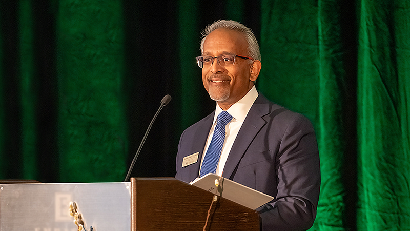 Honorable Mustafa T. Kasubhai, JD ’96 stands behind a lecturn