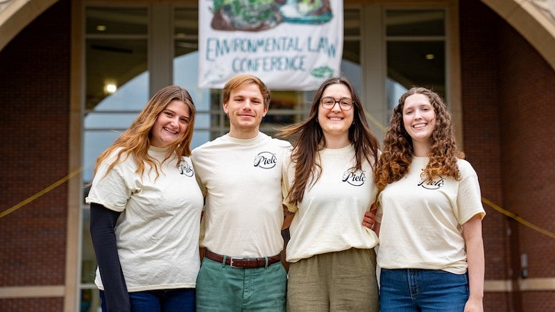 PIELC Conference Student Volunteers Stand Under Banner at Law School