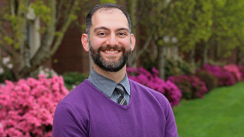 a smiling professor Fakhri in front of brightly colored flowers