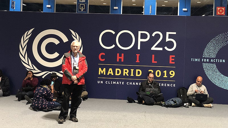 John Bonine in front of COP25 sign