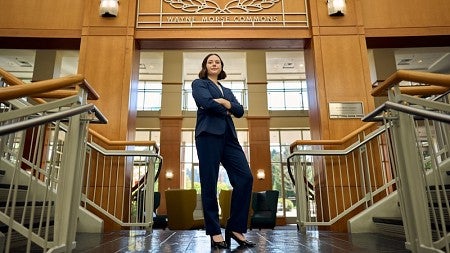 Haley Cook, JD '25, stands at the foot of the stairwell in front of the Wayne Morse Commons sign.