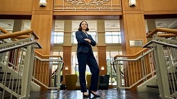 Haley Cook, JD '25, stands at the foot of the stairwell in front of the Wayne Morse Commons sign.