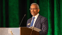 Honorable Mustafa T. Kasubhai, JD ’96 stands behind a lecturn