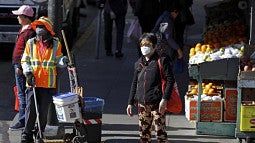 A masked worker and shopper wait for a street signal on Jan. 31, 2020, in the Chinatown district of San Francisco.