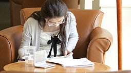 girl studying in a chair next to a window