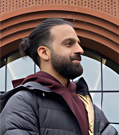 Young man with longer hair pulled back into a knot and standing outside the law school