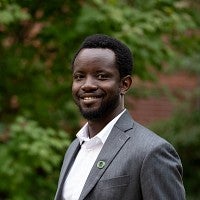 headshot of Professor Joel Sati with greenery in the background