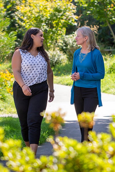 Professor Suzanne Rowe and Nicole Curtis walking and talking together outdoors on a sunny day