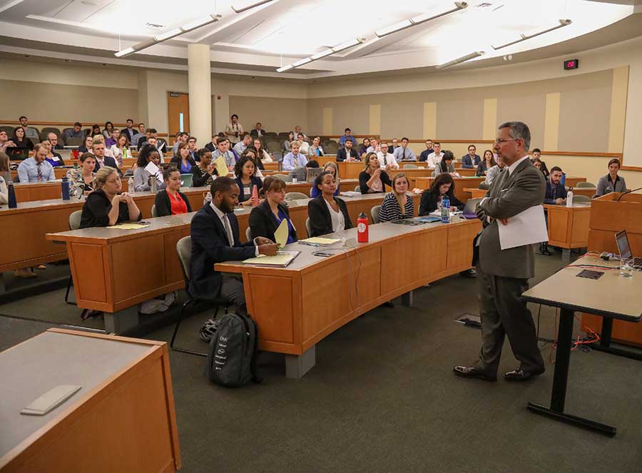Judge John V. Acosta speaks to a large classroom full of law students.