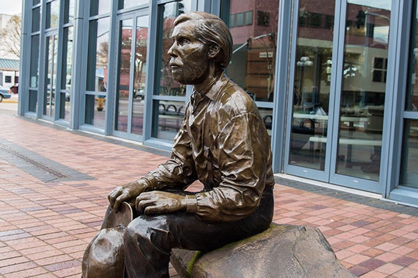 bronze statue of a man sitting on a bench