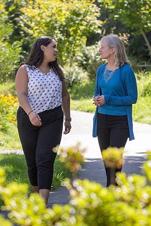 Professor Suzanne Rowe and Nicole Curtis walking and talking together outdoors on a sunny day