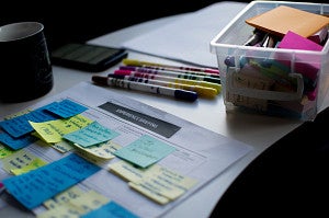sticky notes on paper document beside pens and a box of office supplies