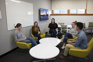 students sitting together around a white coffee table
