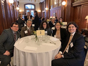 Judge Acosta and law students sitting together at a table at a reception
