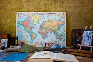 World map with books, an easel, and paint in front