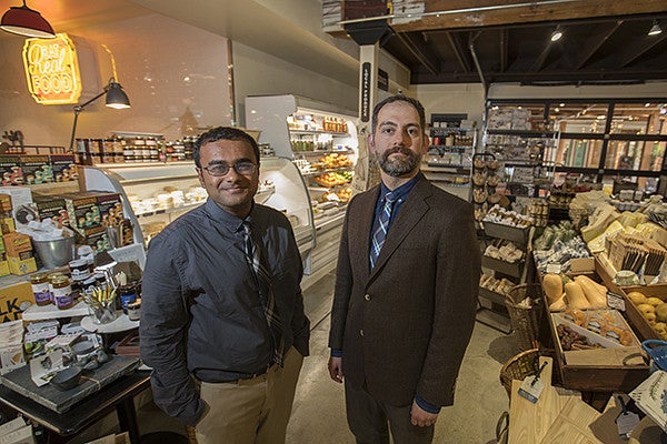 Professor Fakhri and Alumnus Sharath Patil standing amongst good in a marketplace