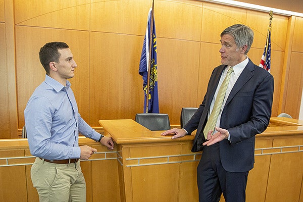 Professor and student standing in front of the bench in the mock court classroom