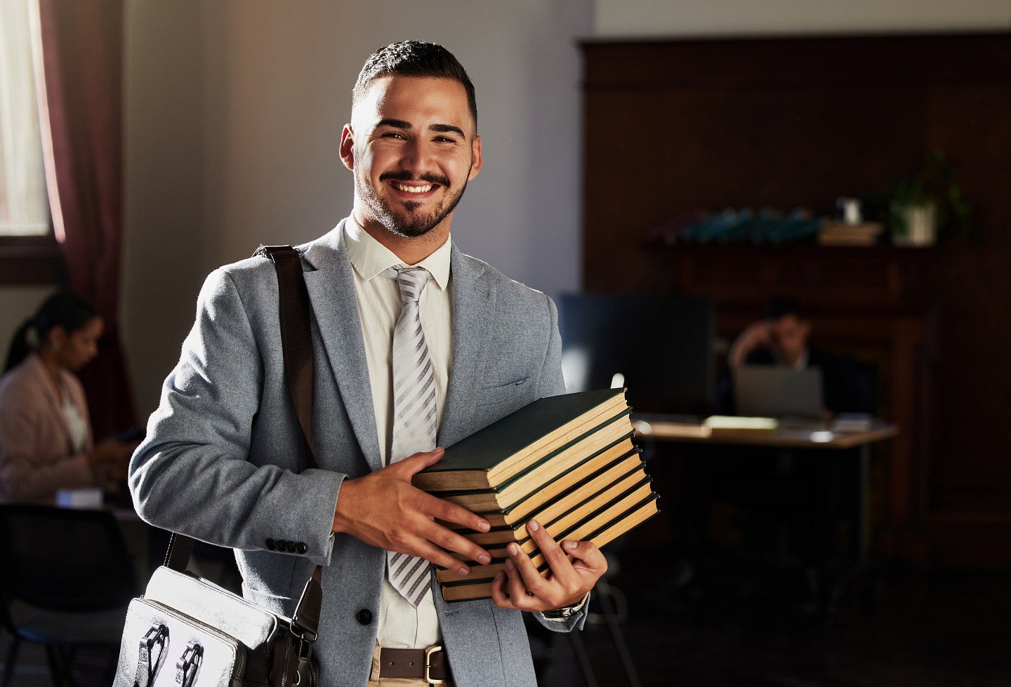 Law student smiling and holding a stack of books
