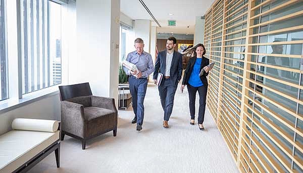 Three people carrying notebooks walking down a hallway
