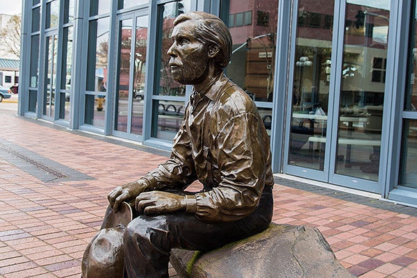 bronze statue of a man sitting on a bench