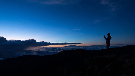 dark figure silhouetted against a brilliant blue sunrise
