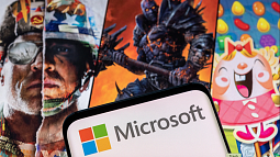 Microsoft logo on a device held in front of posters of Blizzard games like Call of Duty, and Candy Crush